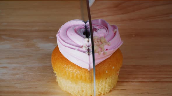 Woman Cuts a Cupcake in Two at a Candy Store. Cooking Dessert in a Pastry Shop. Close-up.