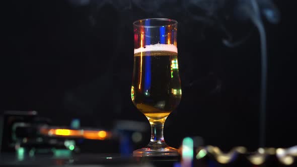 Disco Lights on Beer Glass Cigarette Smoke and Gramophone With Vinyl Record alt