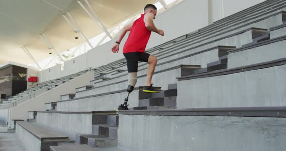 Caucasian disabled male athlete with prosthetic leg training, running up stairs alt