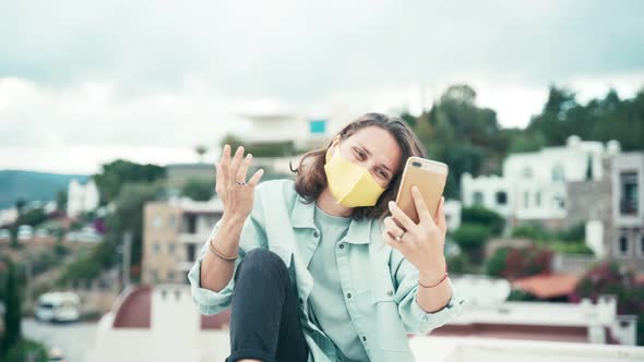Young Woman in Yellow Mask Recording Video for Social Media with Her Smartphone alt