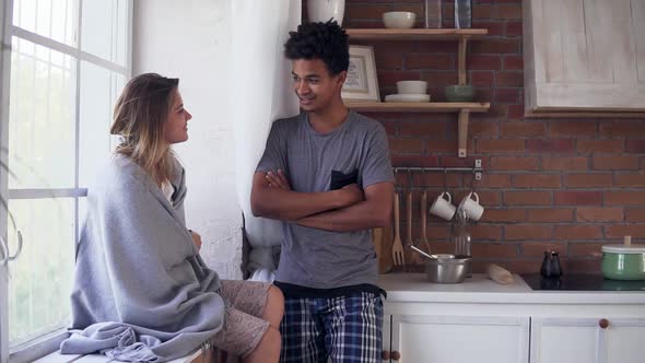 Handsome Multiethnic Couple Talking in the Kitchen in the Morning alt