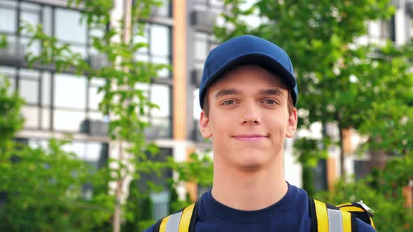 Close Up Smiling Young Man Courier Delivery with Thermal Backpack Looking Camera alt