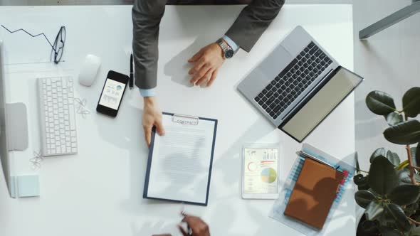 Top Down of Two Business Partners Signing Contract and Shaking Hands alt