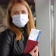 A Woman in a Mask at the Airport She Shows Her Passport with a Plane Ticket - VideoHive Item for Sale