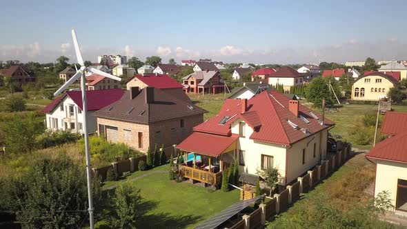 Aerial View of a Residential Private House with Solar Panels on Roof and Wind Generator Turbine alt