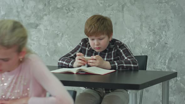 A Young Girl in a Classroom Concentrating on Her Test, While Her Classmate Playing Games on alt