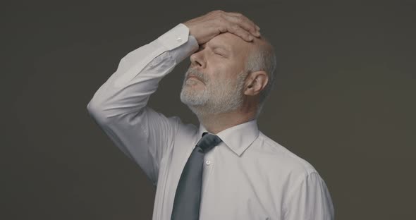 Disappointed businessman touching his forehead, he has made a mistake and feels regretful