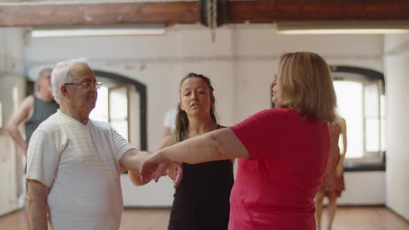 Front View of Dance Teacher Teaching Senior Couple How to Move alt