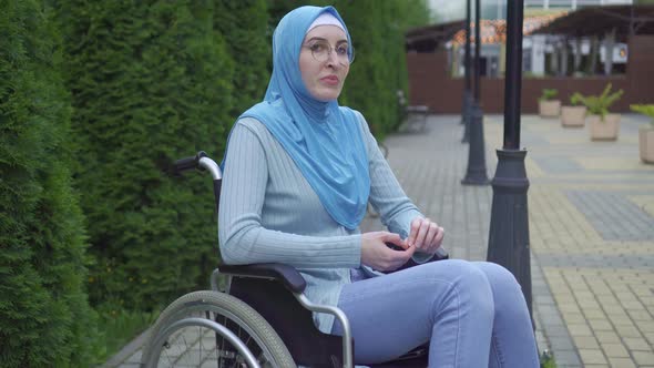Portrait Lonely Sad Young Muslim Woman Disabled in a Traditional Scarf Sitting in a Wheelchair in alt