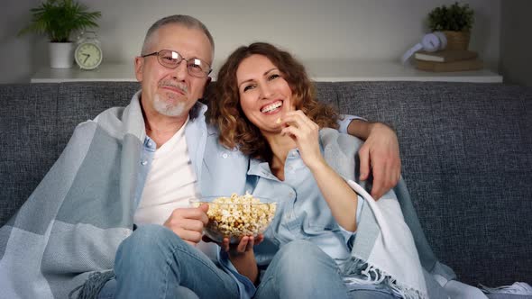 A Cheerful Happy Middleaged Couple Watches Comedy on TV