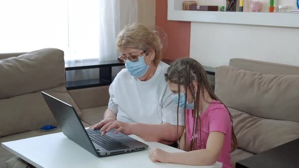 A Little Girl Teaches Her Grandmother To Work on a Laptop . Social Distancing and Self-isolation in
