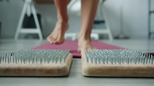 Female Legs Walking on Yoga Mat Then Stepping on Sadhu Board Indoors at Home alt