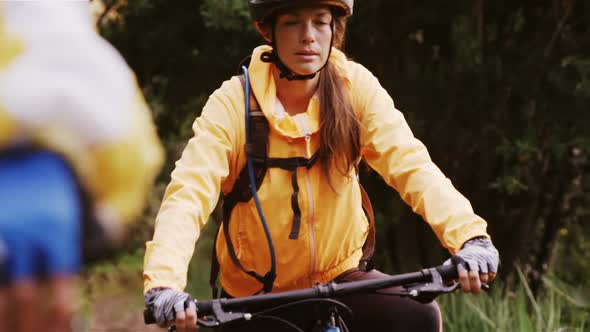 Mountain biking couple riding in the forest on a sunny day alt