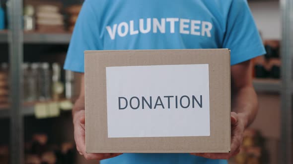 Close Up of Food Bank Worker Holding Donation Box in Hands alt