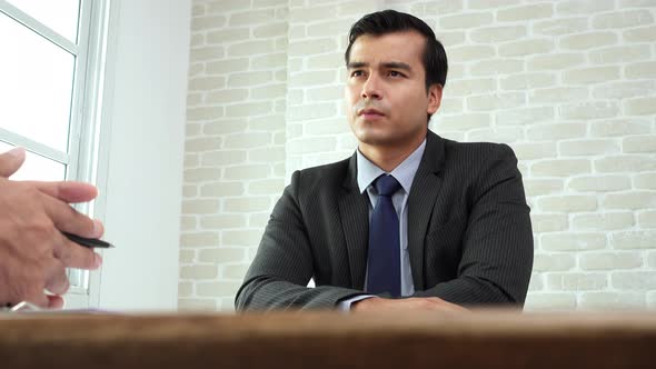 Handsome Hispanic businessman consultant in formal suit seriously listening to his partner