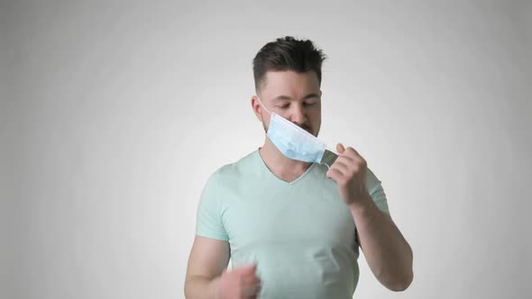 Bearded Man Takes Off Medical Mask and Makes Deep Breath on Grey Background