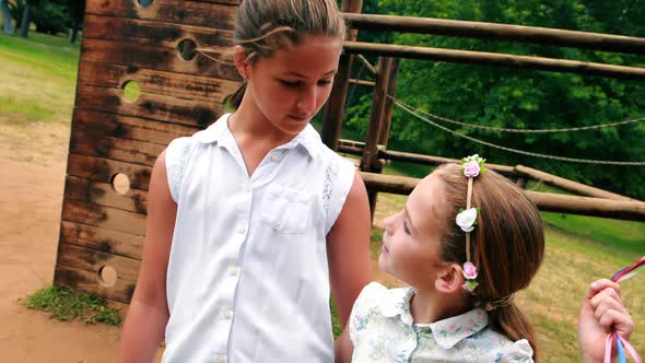 Two girls smiling while holding balloons in park alt