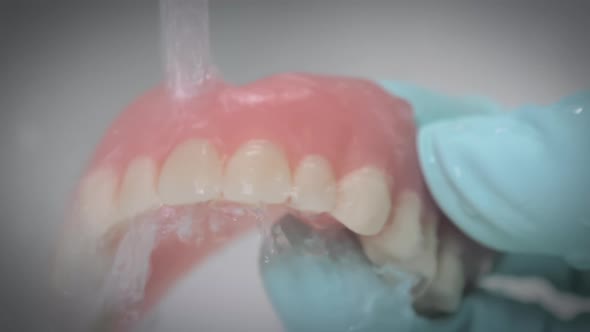 Closeup Shot Showing Washing of Dentures Under Running Water
