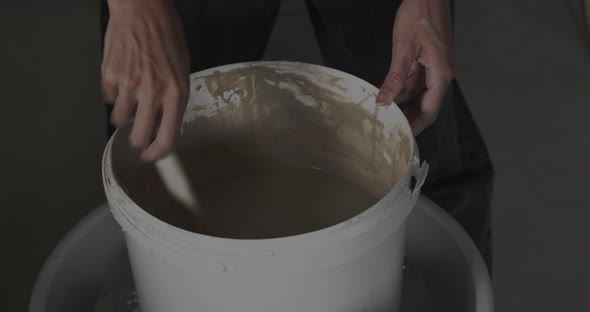Hands Stirring Clay Bucket