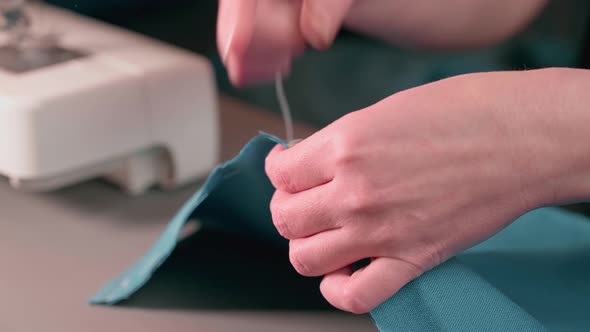 Housewife hands basting green fabric. Repair of clothes at home.