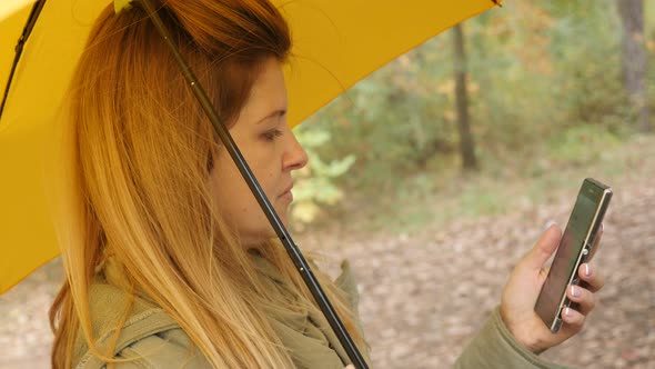 Beautiful blonde female outdoor using mobile phone while raining 4K 3840X2160 UltraHD footage - Blon alt