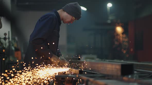 A Factory Worker Grinds the Metal After Welding alt