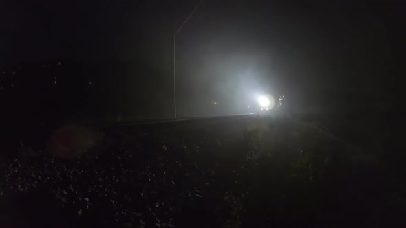 Trains Searchlight Shines Through the Night Fog. The Train Gives a Sign