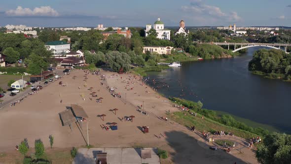 Summer flight over the beach and the river. In the background are churches and a bridge. alt