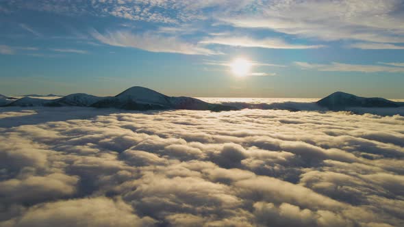 Aerial view of vibrant sunrise over white dense fog with distant dark peaks of Carpathian alt