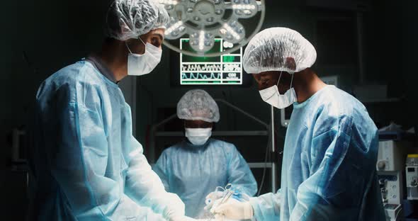 A Team of Surgeons Perform an Operation in a Bright Operating Room alt