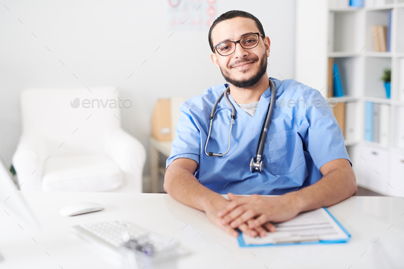 Middle-Eastern Doctor Posing at Desk and Smiling - Stock Photo - Images