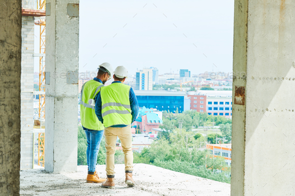 Men in hardhats at construction site of apartment building - Stock Photo - Images