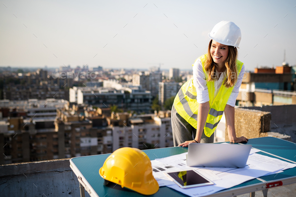 Young female construction specialist engineer reviewing blueprints at construction site - Stock Photo - Images
