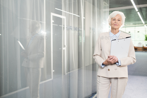 Confident senior business lady with folder in office - Stock Photo - Images