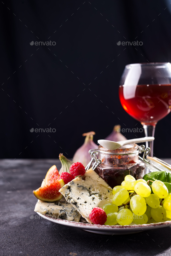 Assortment Of Cheese Berries And Grapes With Red Wine In Glasses