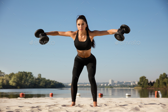 Young fitness female exercise with kettle bell. Caucasian woman doing  crossfit workout at gym. Stock Photo