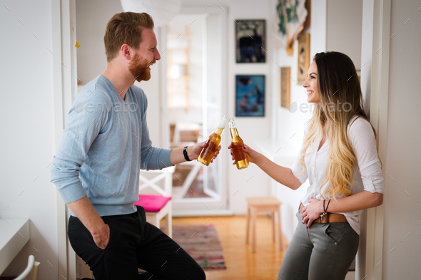 Happy couple drinking beer and toasting at home - Stock Photo - Images