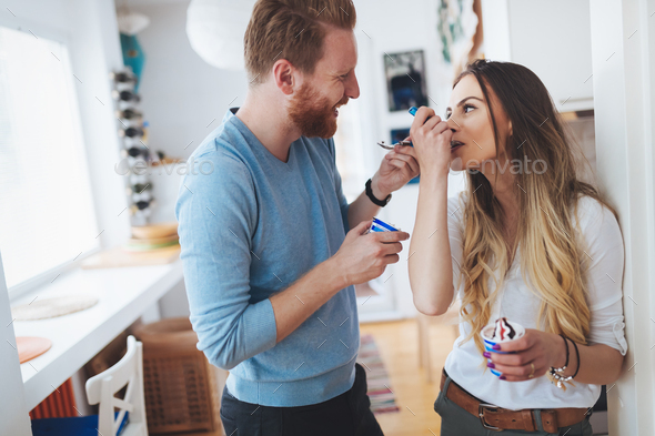 Couple having fun and laughing at home while eating ice cream - Stock Photo - Images