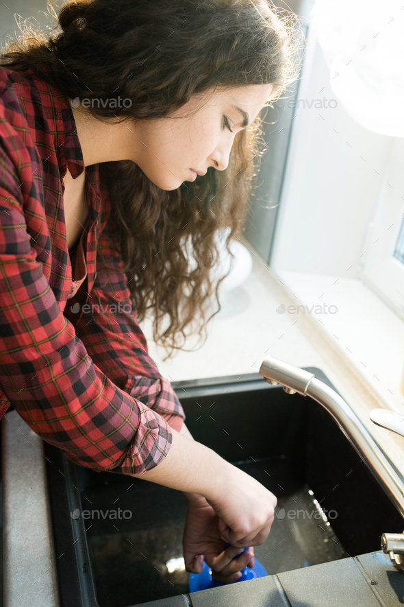 A female plumber fixing the kitchen sink with a plunger, Stock image