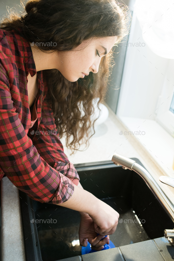 Woman Using Plunger In Kitchen Sink Stock Photo