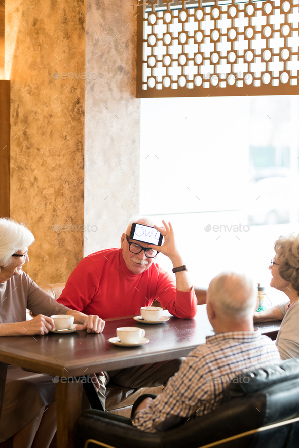 Elderly friends playing charades in cafe