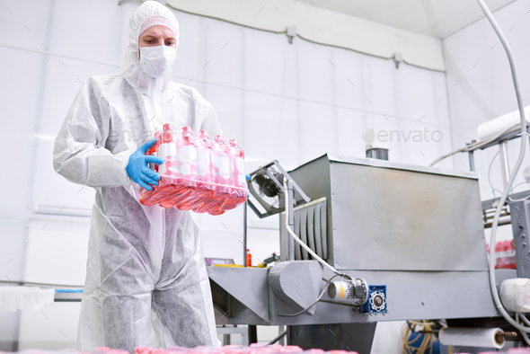 Factory worker carrying pack of bottles