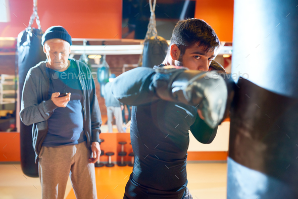 Man boxing bag with trainer on workout - Stock Photo - Images