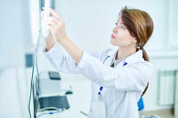 Doctor standing and examining X-ray - Stock Photo - Images