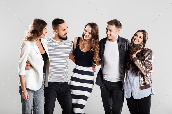 Company of friends in fashionable casual clothes stand together and talk on a white background in