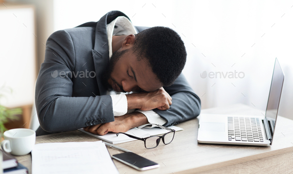 Tired african american businessman having a nap at workplace