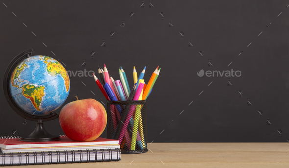 Stationery, world globe and apple over black board - Stock Photo - Images