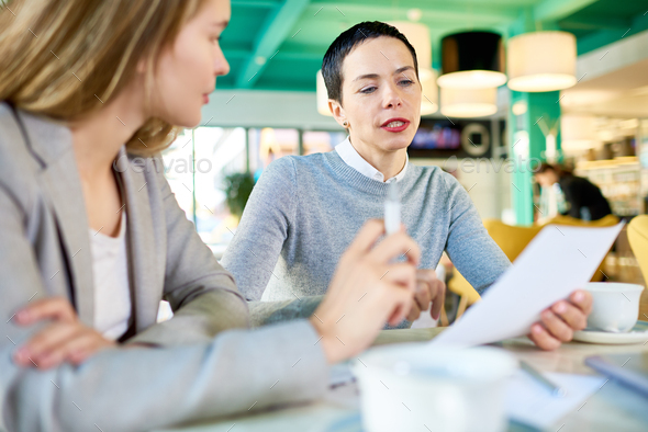 Two Business Women Reading Documents in Cafe - Stock Photo - Images