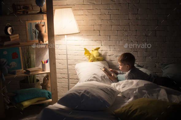 Little Boy Reading Book at Night - Stock Photo - Images