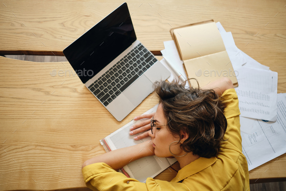 Top View Of Young Tired Woman Fall Asleep On Desk With Laptop And